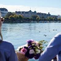 Un couple est assis au bord d’un lac et regarde les bateaux 