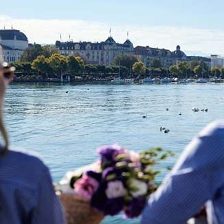 Ein Pärchen sitzt am Rande eines Sees und blickt auf die Boote 