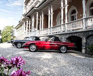 Zwei Oldtimer stehen im Oldtimer Urlaub vor einem alten Gebäude Zwei Oldtimer stehen im Oldtimer Urlaub vor einem alten Gebäude