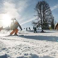 Eine Gruppe Skifahrer fährt im Schneeurlaub die Piste hinunter  Eine Gruppe Skifahrer fährt im Schneeurlaub die Piste hinunter
