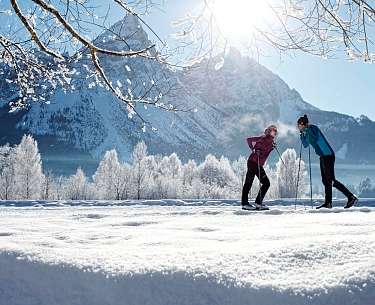 Ein Pärchen steht mit Langlaufski im romantischen Winterurlaub in Schnee Ein Pärchen steht mit Langlaufski im romantischen Winterurlaub in Schnee
