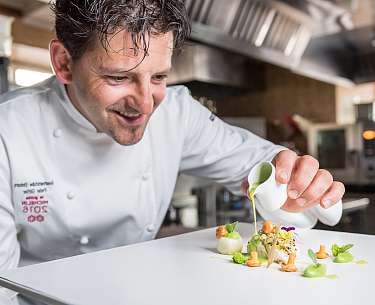 Der Chefkoch richtet das luxuriöse Essen in einem Hotel mit Sterneküche an Der Chefkoch richtet das luxuriöse Essen in einem Hotel mit Sterneküche an