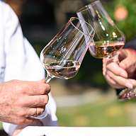 Zwei Gäste des Romantik Hotels stoßen mit Weingläsern an 