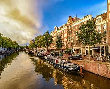 Abendfoto von farbigen Häusern im niederländischen Stil mit Spiegelung im Wasser in Amsterdam Abendfoto von farbigen Häusern im niederländischen Stil mit Spiegelung im Wasser in Amsterdam