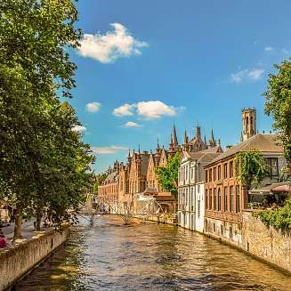 Vue sur un canal bordé de maisons et quelques bateaux sur le fleuve en Belgique