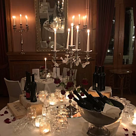 Valentinstag Blick auf einen gedeckten Tisch bei Nacht mit vielen Kerzen, Wein und Rosenblättern