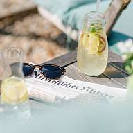 RH Reichshof Sonnenbrille, Zeitung und sommerliche Limonade liegen auf einem Tisch