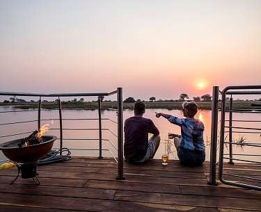 Paar genießt Sonnenuntergang am Kwando, Sambesi-Region, Namibia Paar genießt Sonnenuntergang am Kwando, Sambesi-Region, Namibia