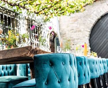 Blaue Stoffstühle stehen an einer Tafel im Außenbereich eines Romantik Hotels Blaue Stoffstühle stehen an einer Tafel im Außenbereich eines Romantik Hotels