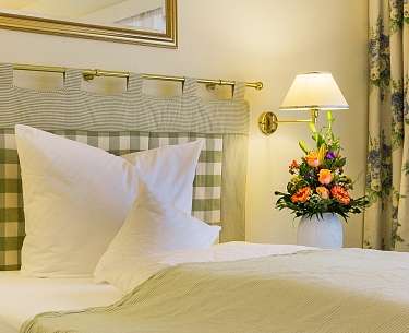 Einzelzimmer  Einzelzimmer mit grün gelb kariertem Bett und Blumenstrauß