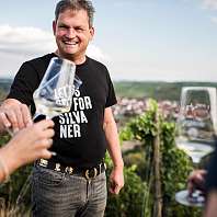 MainGenussTrail c hannes niederkofler web 5556 Ralph Düker with a glass of white wine in front of the vineyard