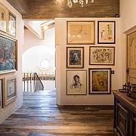 Flur einer Kunstgalerie mit Gemälden an den Wänden und Skulpturen auf Tischen