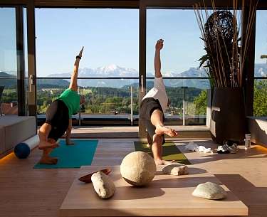 Yoga mit Aussicht im Panorama Spa Zwei Personen beim Yoga in einem Fitness Raum mit Aussicht auf die Salzburger Bergwelt im Hintergrund