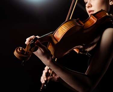 Musikerin, die auf einer dunklen Bühne Geige spielt Musikerin, die auf einer dunklen Bühne Geige spielt